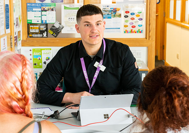 Careers adviser talking to clients sat facing the camera in a careers office